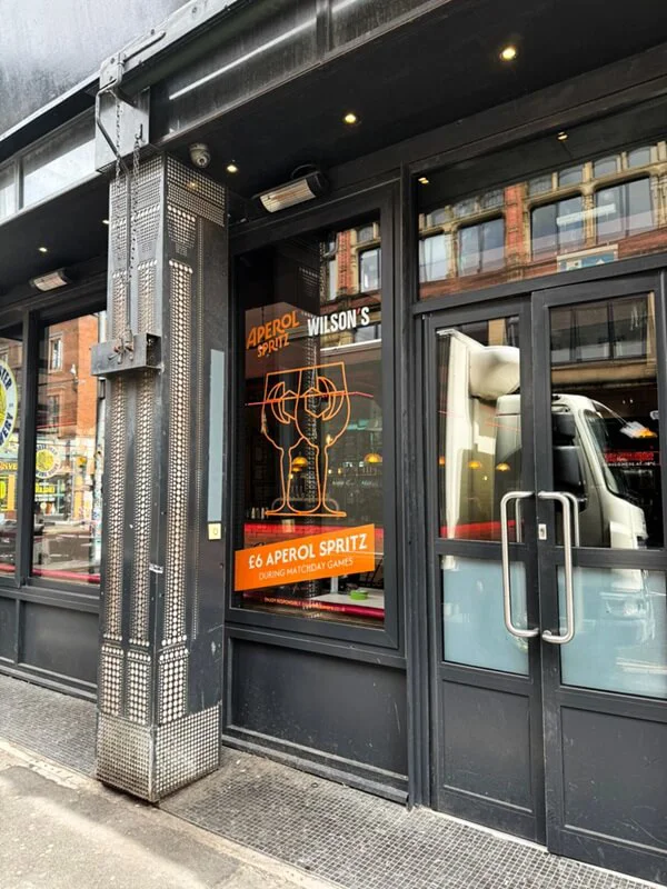 An image of a storefront's limited window space and signage showing two wine glasses.